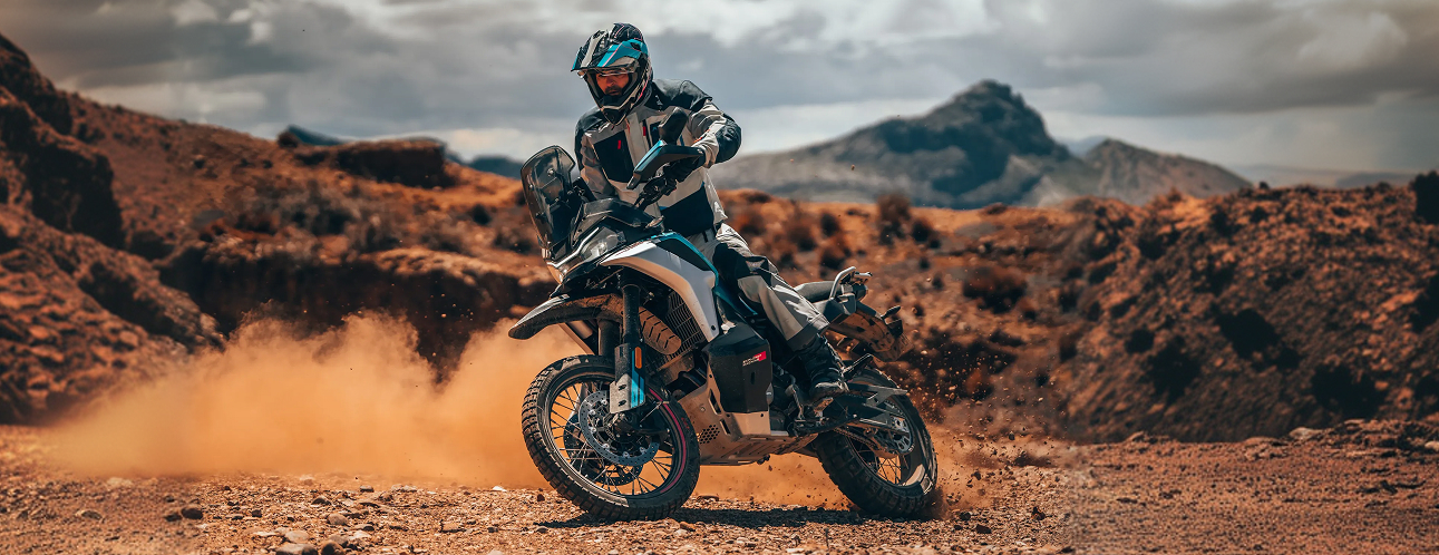 CFMoto en Martinez - CFMoto 800MT-X circulando sobre terreno de ripio con polvo y piloto equipado