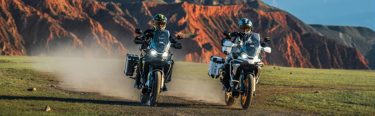 CFmotoMartinez - dos motos CFMOTO 700MT ADV avanzando sobre tierra con conductores equipados y fondo montañoso